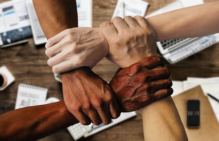 Handen met verschillende huidskleur houden elkaar vast
